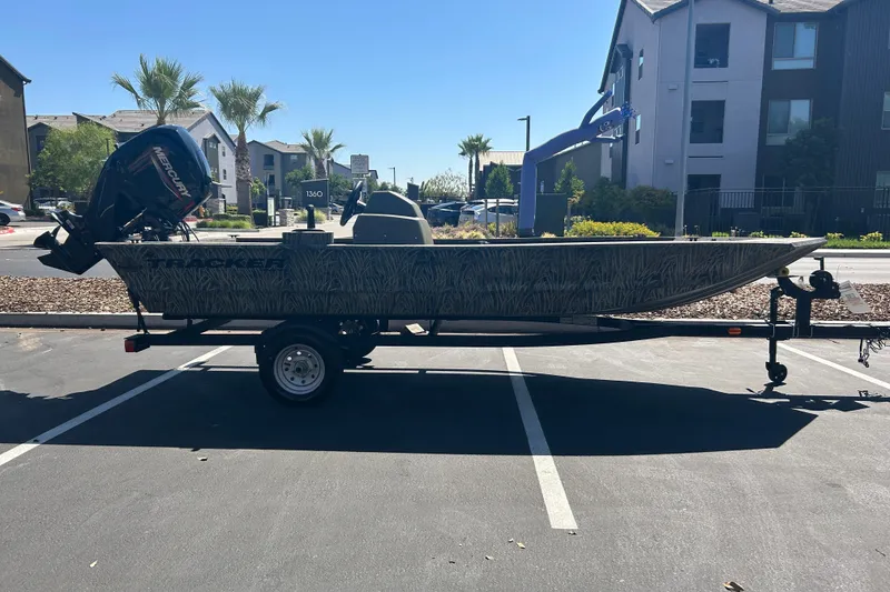 The Image of 2026 Tracker Grizzly 1648 SC boat on trailer in parking lot, surrounded by buildings and palm trees. - 0