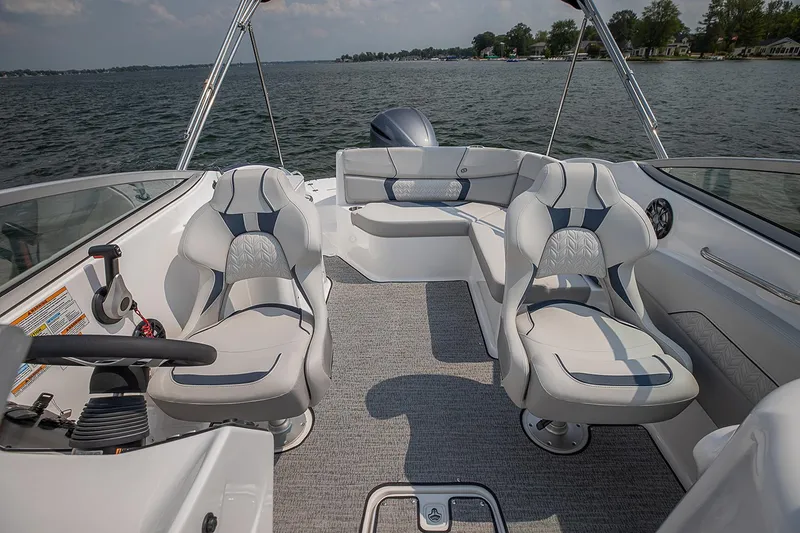 Slide: The Image of Manufacturer Provided Image: 2021 Hurricane SunDeck 2400 OB boat interior with seating and steering wheel on a lake. - 11