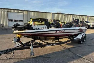 Slide: The Image of 2015 Triton 22 TrX boat on trailer, parked outside a warehouse. - 4