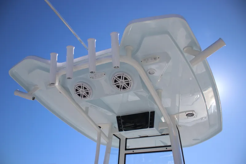 Slide: The Image of 2026 Tidewater 2300 Carolina Bay boat top view with rod holders and speakers against blue sky. - 17