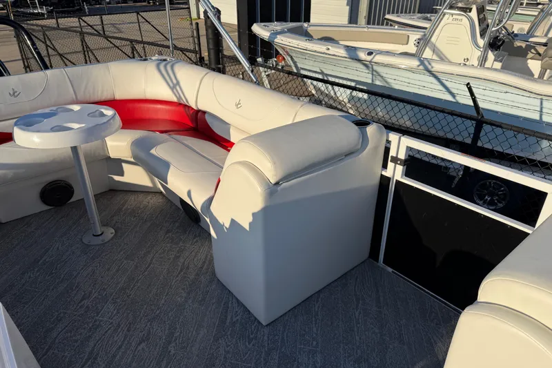 Slide: The Image of 2021 JC Spirit 221TT pontoon boat interior with white and red seating, table, and flooring. - 18