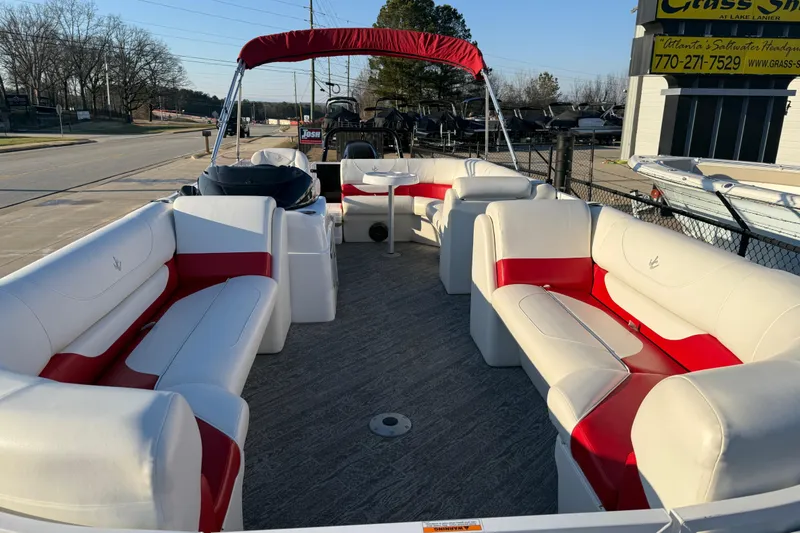 Slide: The Image of 2021 JC Spirit 221TT pontoon boat with red and white seating, parked outdoors. - 11