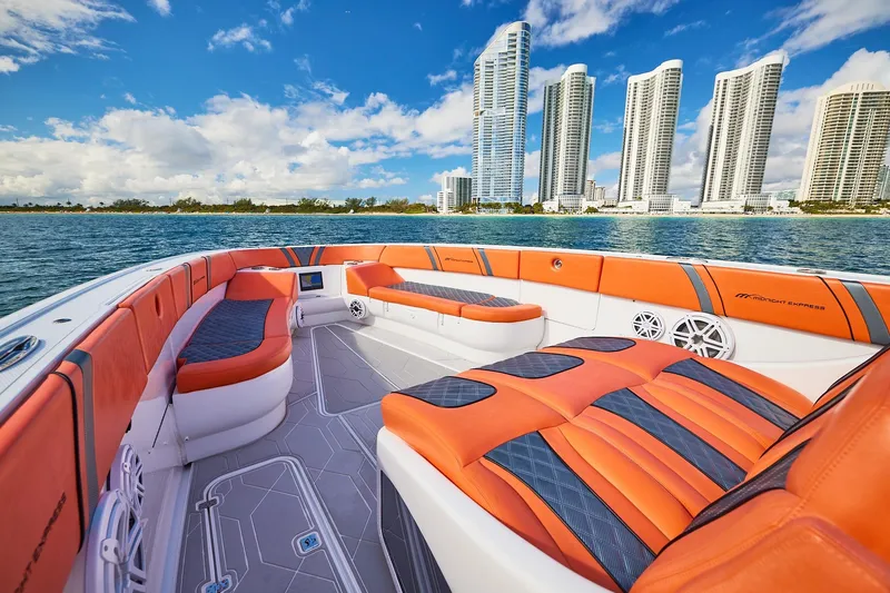 Slide: The Image of Luxurious Midnight Express 43 Open boat with vibrant orange seating, city skyline in background. - 11