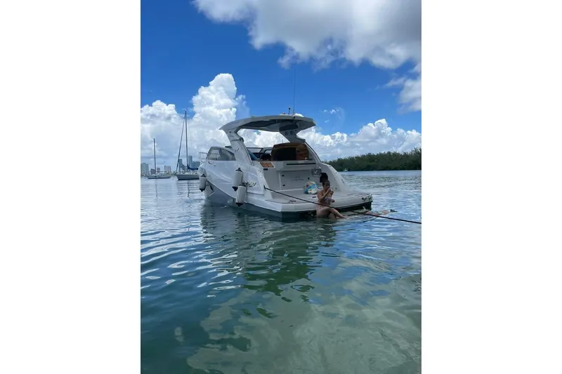 Slide: The Image of 2023 NX Boats NX340 yacht on water, person relaxing at stern, clear sky. - 3