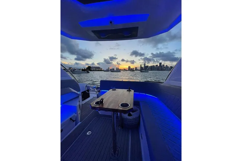 Slide: The Image of 2023 NX Boats NX340 interior with blue lighting, overlooking city skyline at sunset. - 5