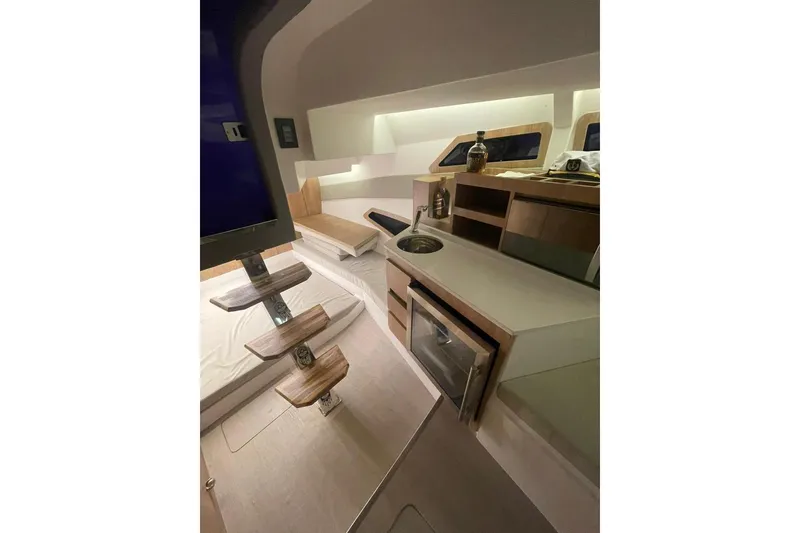 Slide: The Image of 2023 NX Boats NX340 interior with modern kitchen, wooden steps, and cozy seating area. - 6