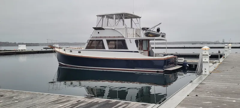 The Image of 1989 Duffy Wilbur 42 Flybridge Cruiser docked at a marina on a cloudy day. - 0