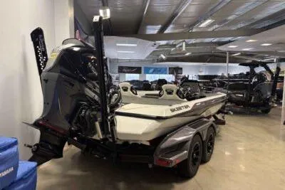 Slide: The Image of 2026 Skeeter FXR21 PRO boat in showroom, rear view with motor and dual axles. - 2