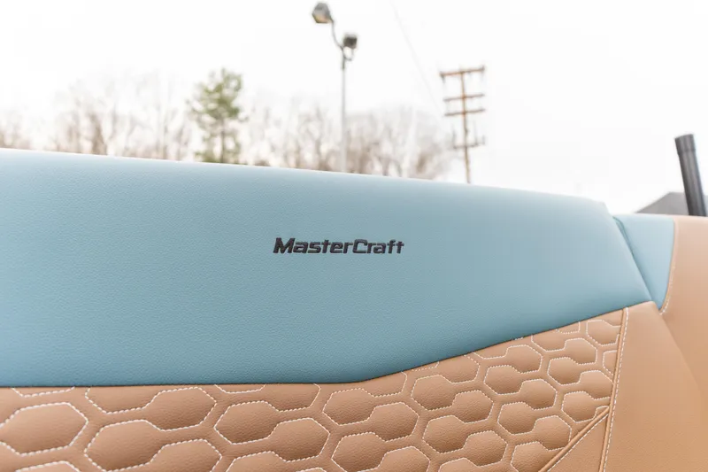Slide: The Image of 2026 MasterCraft NXT23 boat interior with blue and tan upholstery, featuring hexagonal stitching. - 11