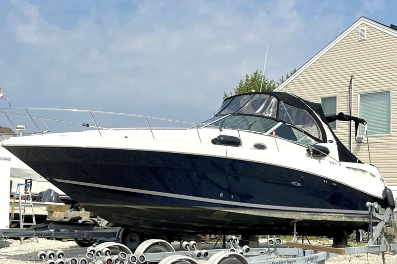 The Image of 2006 Sea Ray 340 Sundancer boat on trailer near house, under clear sky. - 0