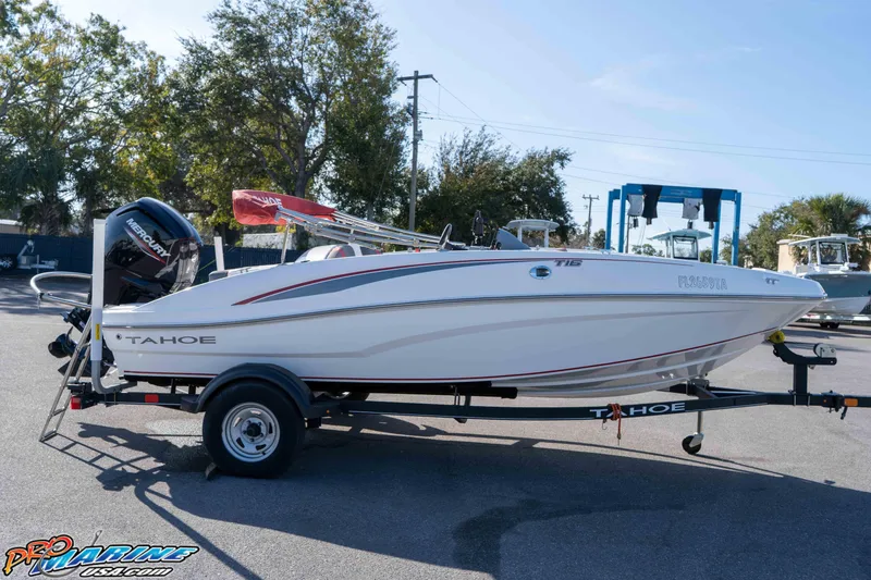 Slide: The Image of 2021 Tahoe T16 boat on trailer, parked outdoors with trees in the background. - 13