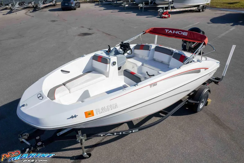 Slide: The Image of 2021 Tahoe T16 boat on trailer, white with red accents, parked outdoors. - 27