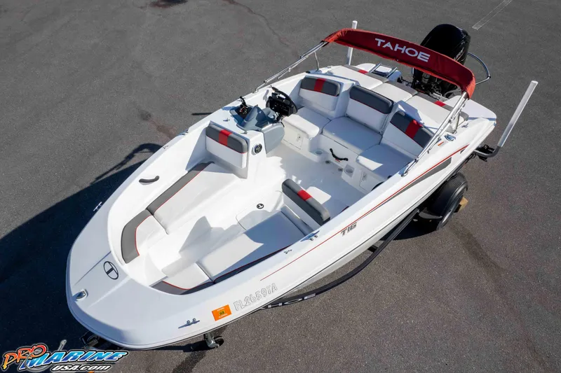 Slide: The Image of 2021 Tahoe T16 boat with red canopy and white seating, parked on asphalt. - 28