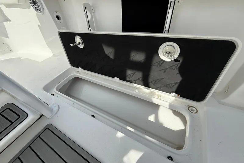 Slide: The Image of 2026 Tidewater 256 LXF boat storage compartment with open lid and sleek interior design. - 7