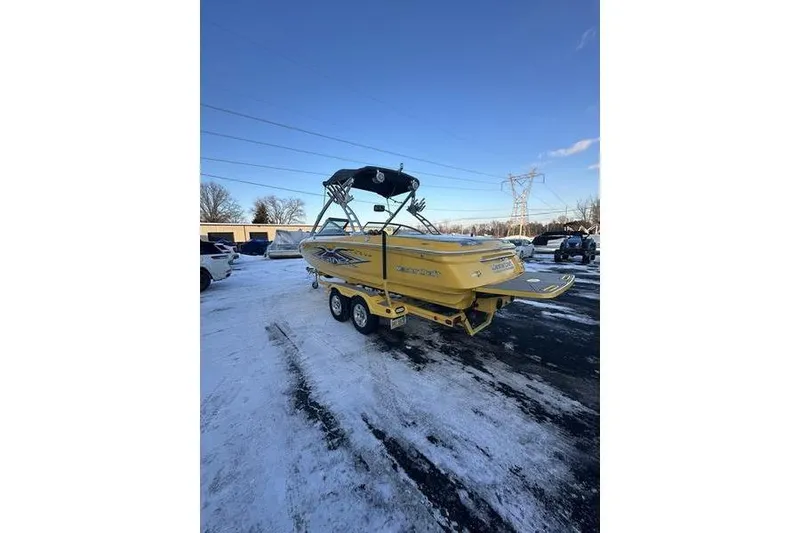 Slide: The Image of 2004 MasterCraft XStar 23 boat in snowy parking lot, yellow with trailer. - 23