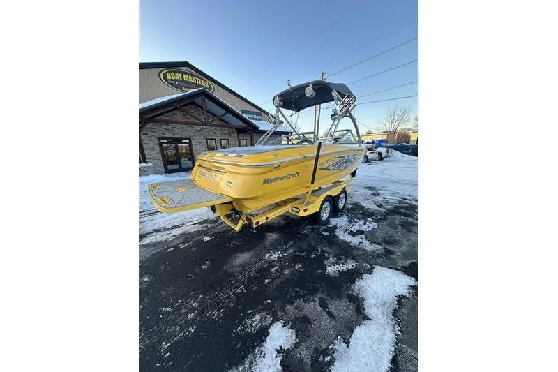 Slide: The Image of 2004 MasterCraft XStar 23 boat in yellow, parked on snowy pavement near Boat Masters building. - 3