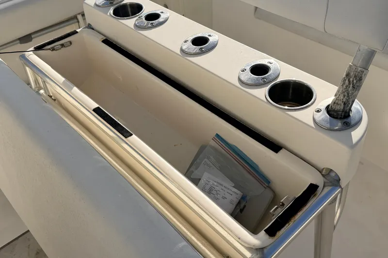 Slide: The Image of 2020 Cobia 220 Center Console boat storage compartment with cup holders and documents. - 15