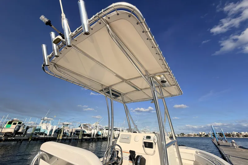 Slide: The Image of 2020 Cobia 220 Center Console boat with T-top, docked under clear blue sky. - 18