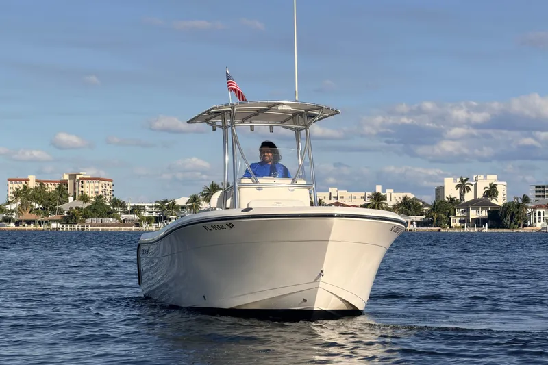 Slide: The Image of 2020 Cobia 220 Center Console boat on water, with cityscape background. - 2
