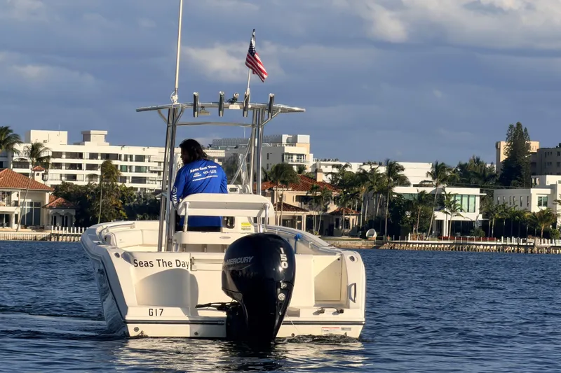 Slide: The Image of 2020 Cobia 220 Center Console boat on water, cityscape background, American flag flying. - 4