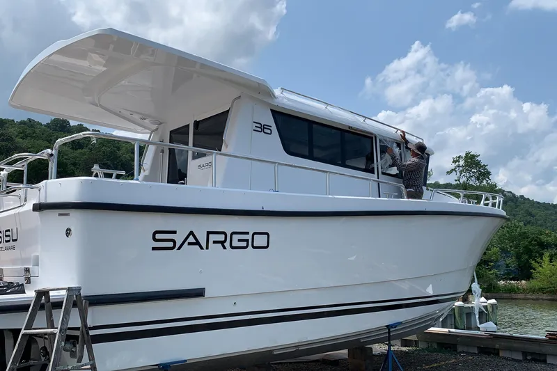 Slide: The Image of 2021 Sargo 36 boat docked with person working on the exterior. - 1