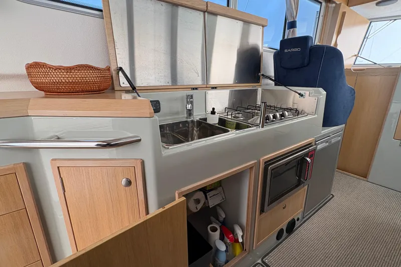 Slide: The Image of Modern kitchen area in a 2021 Sargo 36 boat with stove, sink, and storage. - 18