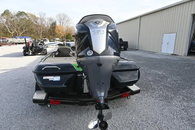 Slide: The Image of 2022 Skeeter ZXR20 boat with powerful outboard motor, parked on gravel near a warehouse. - 9