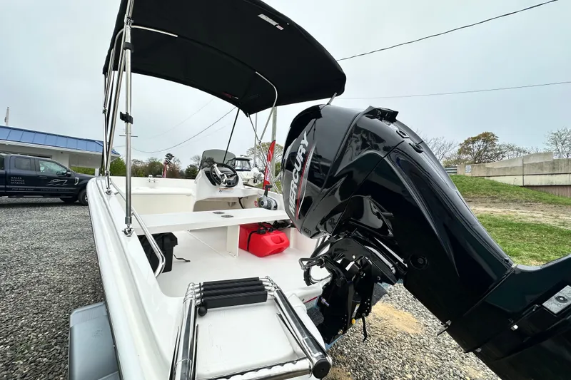 Slide: The Image of 2026 Boston Whaler 130 Super Sport with Mercury engine, parked on gravel lot. - 23