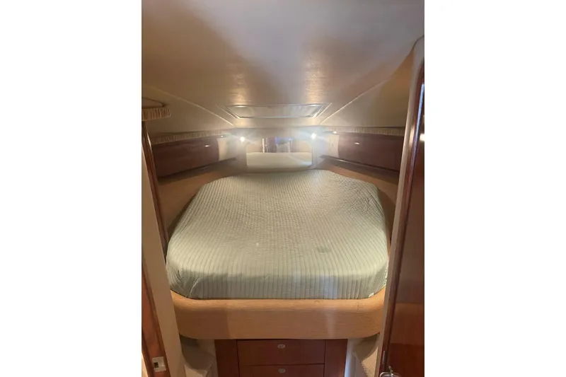 Slide: The Image of 2005 Sea Ray 420 Sundancer cabin interior with bed and wooden cabinetry. - 17