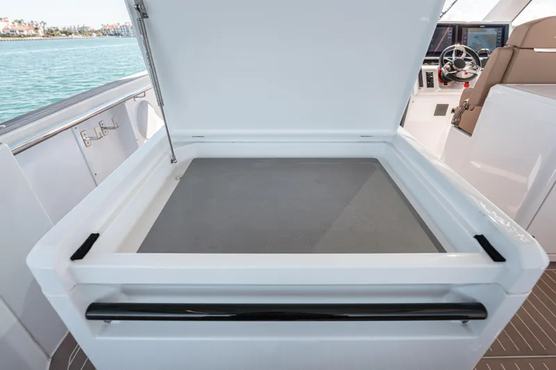 Slide: The Image of 2024 Fjord Boats 53XL open storage compartment on deck, with helm in background. - 22