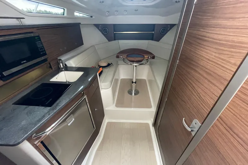 Slide: The Image of 2023 Boston Whaler 325 Conquest cabin interior with kitchenette and seating area. - 12
