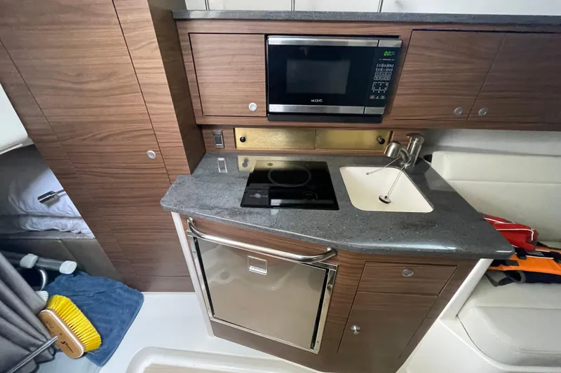 Slide: The Image of 2023 Boston Whaler 325 Conquest galley with microwave, sink, and compact fridge. - 13