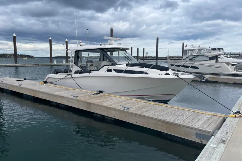 Slide: The Image of 2023 Boston Whaler 325 Conquest docked at marina under cloudy sky. - 2