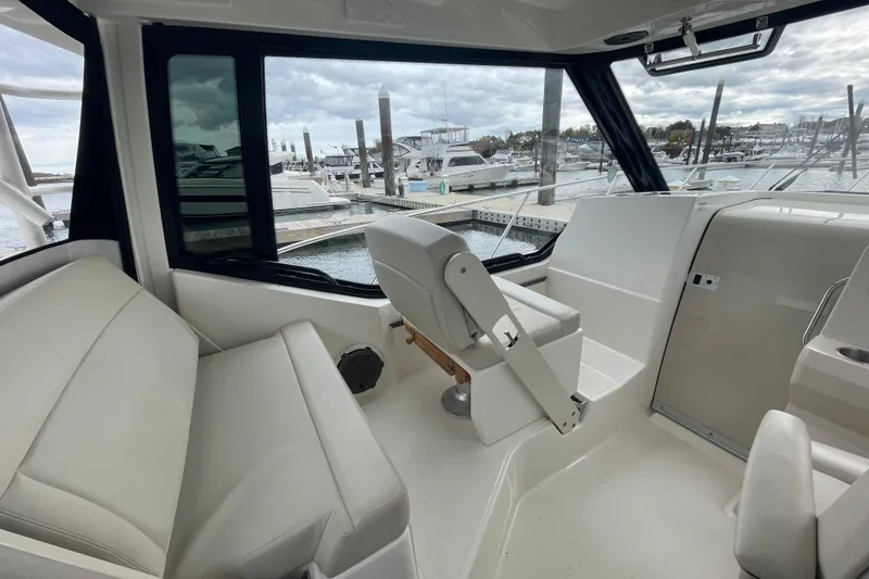 Slide: The Image of 2023 Boston Whaler 325 Conquest interior with seating and helm, docked at marina. - 8