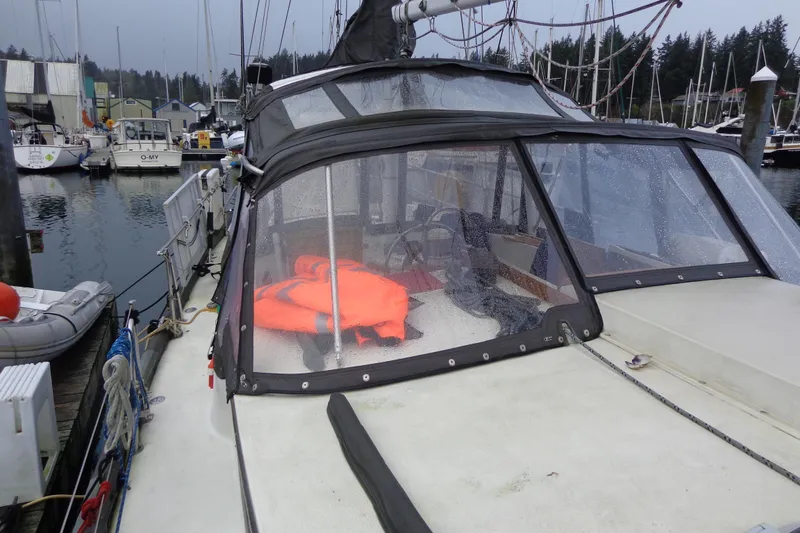 Slide: The Image of 1979 Islander Freeport Center Cockpit Ketch docked, featuring a wet deck and bright orange life jacket. - 10