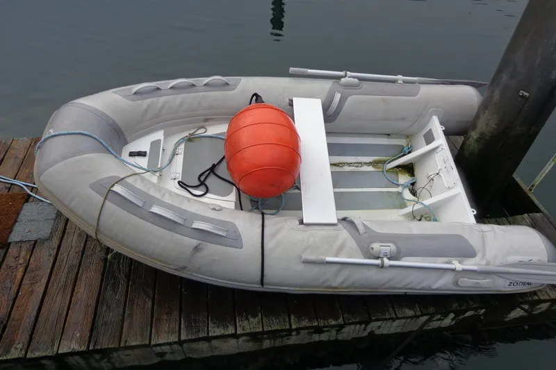 Slide: The Image of Inflatable dinghy with orange buoy on dock, near water. - 16