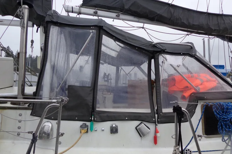 Slide: The Image of 1979 Islander Freeport Center Cockpit Ketch with rain-soaked enclosure and visible life jackets. - 24