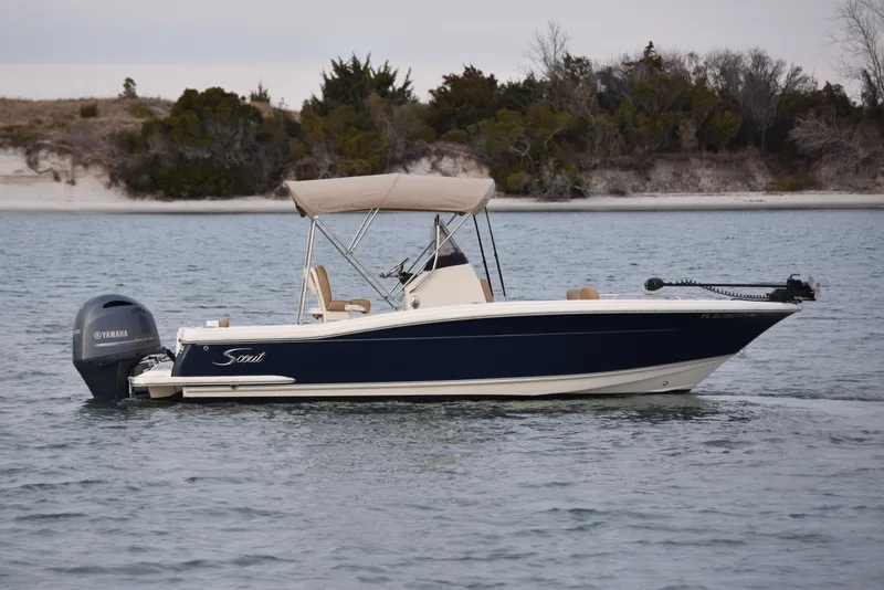 Slide: The Image of 2020 Scout 215 XSF boat on calm water with scenic shoreline background. - 2