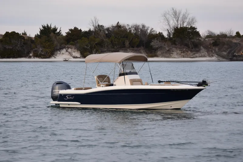 Slide: The Image of 2020 Scout 215 XSF boat on water with canopy, near a wooded shoreline. - 4