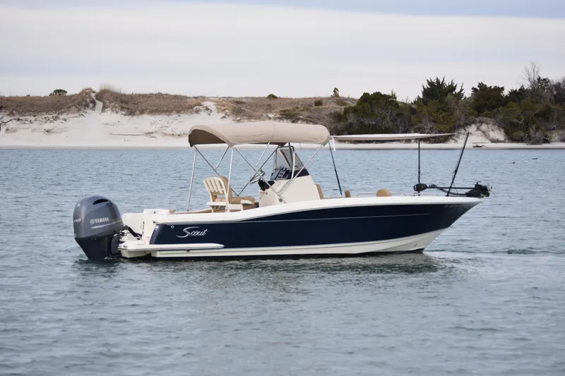 Slide: The Image of 2020 Scout 215 XSF boat on calm water near a wooded shoreline. - 7