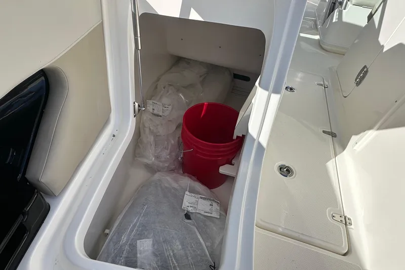 Slide: The Image of Storage compartment in 2026 Boston Whaler 240 Vantage with red bucket. - 12
