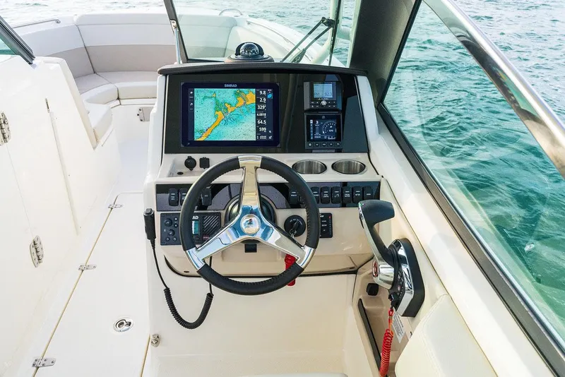 Slide: The Image of Manufacturer Provided Image: 2026 Boston Whaler 240 Vantage helm with navigation display and steering wheel, overlooking water. - 6