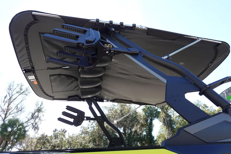 Slide: The Image of 2026 Axis A245 boat with advanced wakeboard tower and canopy, set against a clear sky. - 6