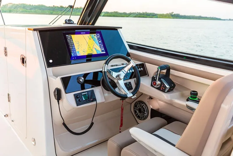 Slide: The Image of Manufacturer Provided Image: 2025 Boston Whaler 330 Vantage helm with navigation display and controls, overlooking serene waters. - 8