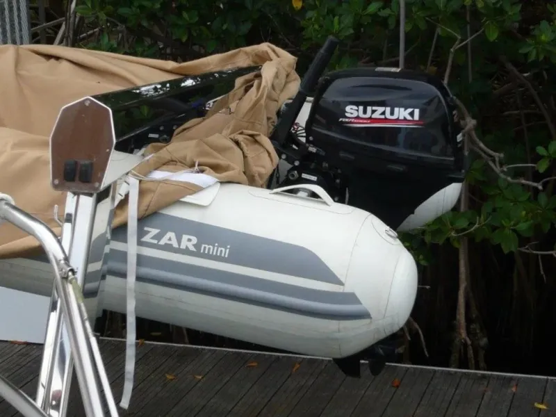 Slide: The Image of Inflatable Zar Mini boat with Suzuki outboard motor, docked near a Cheoy Lee Sloop, 1990 model. - 24