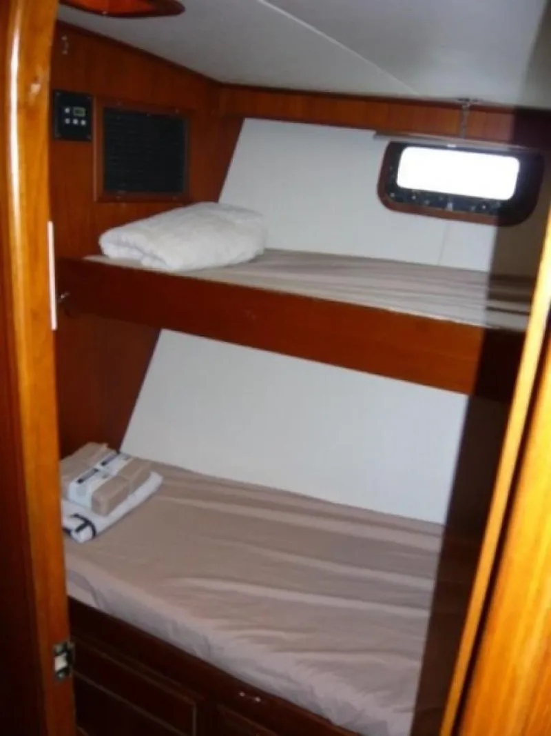 Slide: The Image of 1990 Cheoy Lee Sloop cabin with wooden bunk beds and a small window. - 45