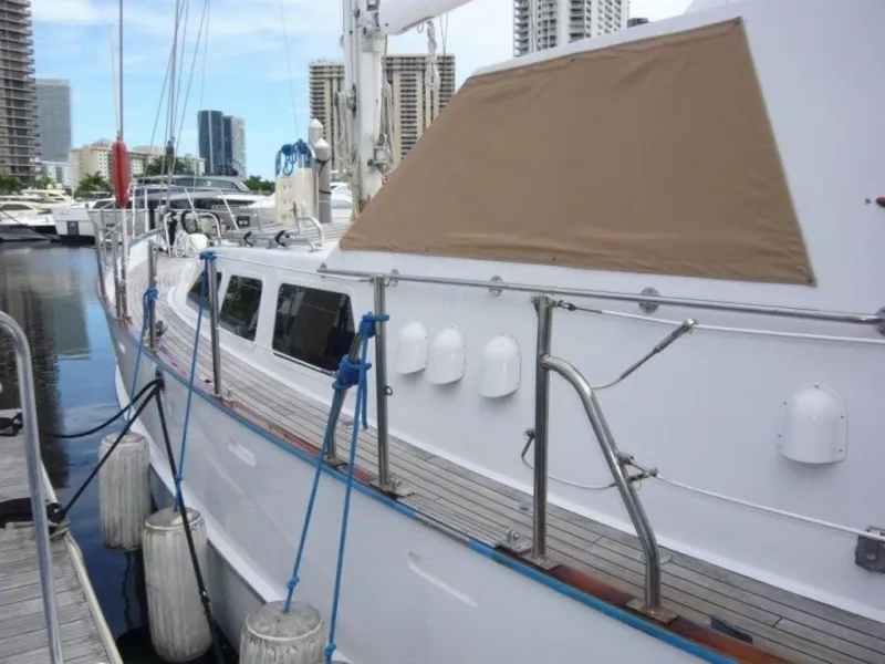 Slide: The Image of 1990 Cheoy Lee Sloop docked at marina with city skyline in background. - 8