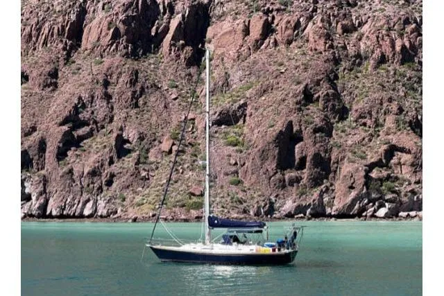 Slide: The Image of Sailboat Hylas Custom 44 (1988) anchored near rocky cliffs in turquoise water. - 53