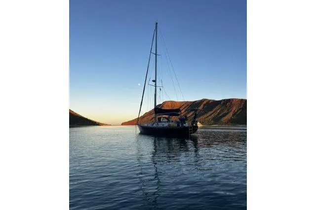Slide: The Image of Sailboat Hylas Custom 44 (1988) on serene water at sunset with mountains. - 57