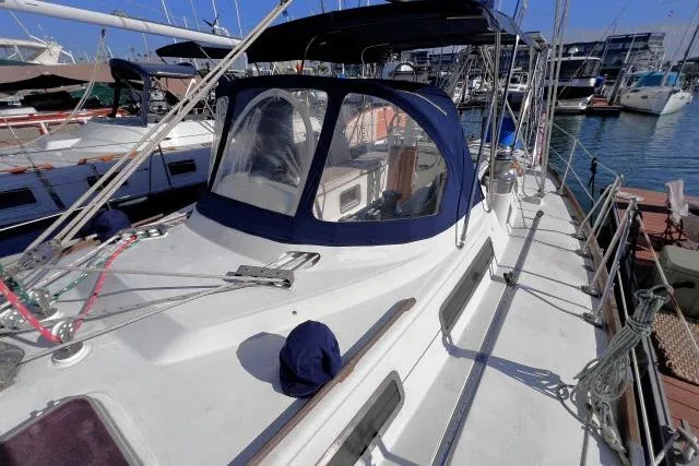 Slide: The Image of 1988 Hylas Custom 44 sailboat docked at marina, featuring blue canopy and sleek design. - 34